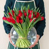 Red tulips in a fish bowl vase