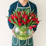 Red tulips in a fish bowl vase