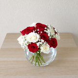 Red and white roses in a fish bowl vase