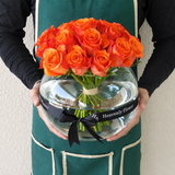 Orange roses in a fish bowl vase