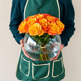 Orange roses in a fish bowl vase