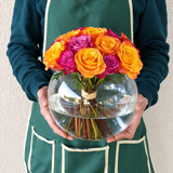 Purple and orange roses in a fish bowl vase