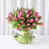 Purple tulips in a fish bowl vase