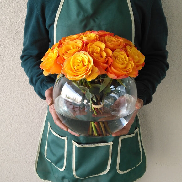 Orange roses in a fish bowl vase