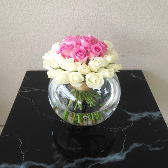 White and pink roses in a fish bowl vase