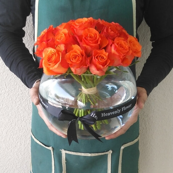 Orange roses in a fish bowl vase