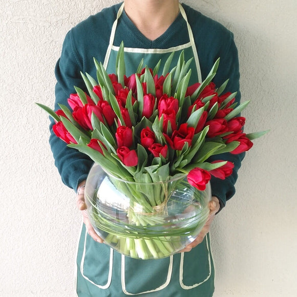 Red tulips in a fish bowl vase