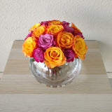 Purple and orange roses in a fish bowl vase