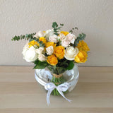 Assorted yellow and white flowers in a fish bowl