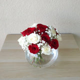 Red and white roses in a fish bowl vase